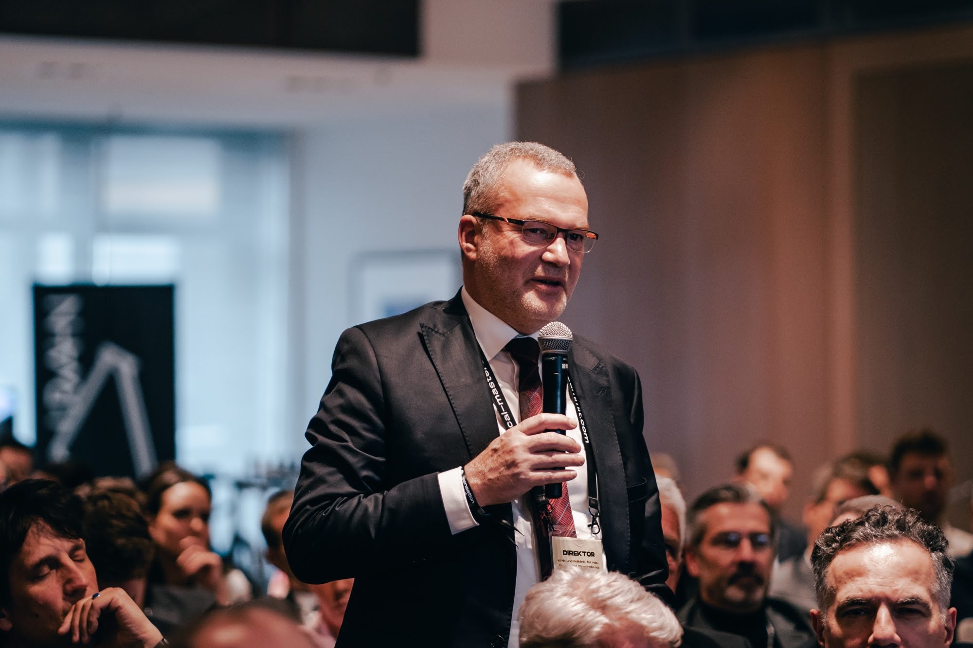 Teilnehmer stellt eine Frage ins Mikrofon während einer Session